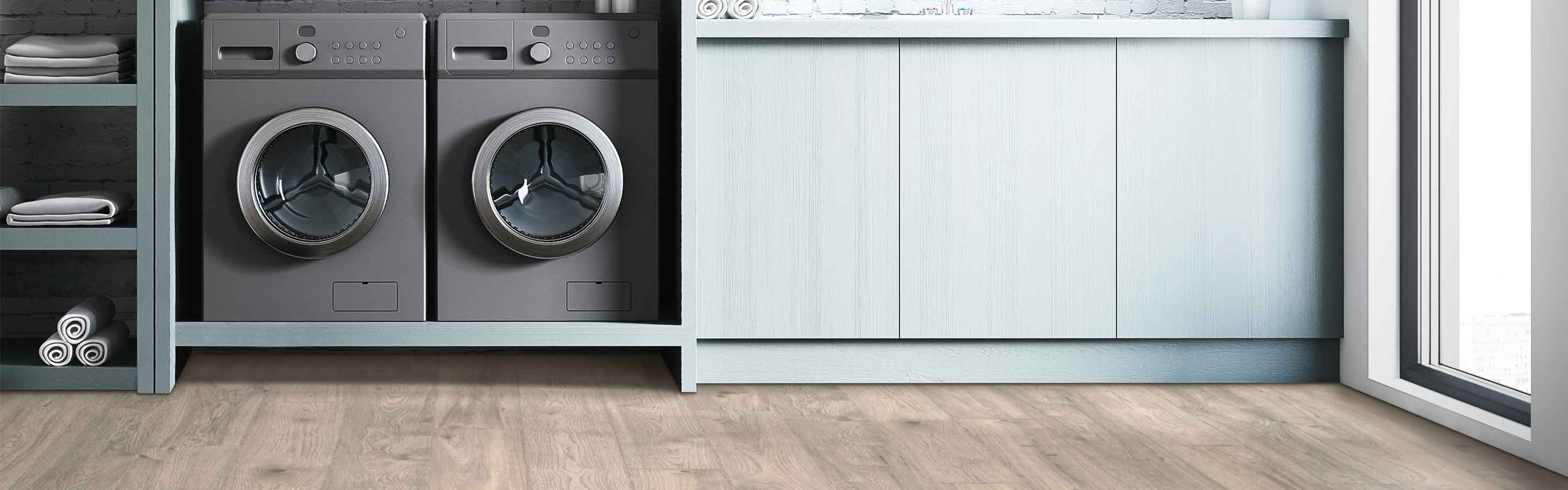 Laminate flooring in modern laundry room with gray cabinetry, sink and washing machines